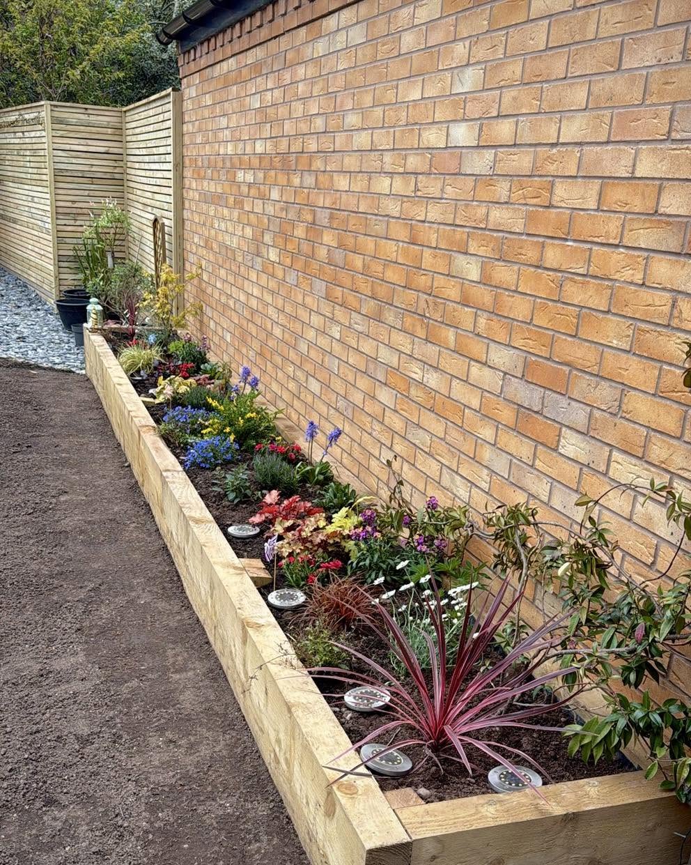 Brick garden wall with sleeper raised bed planting