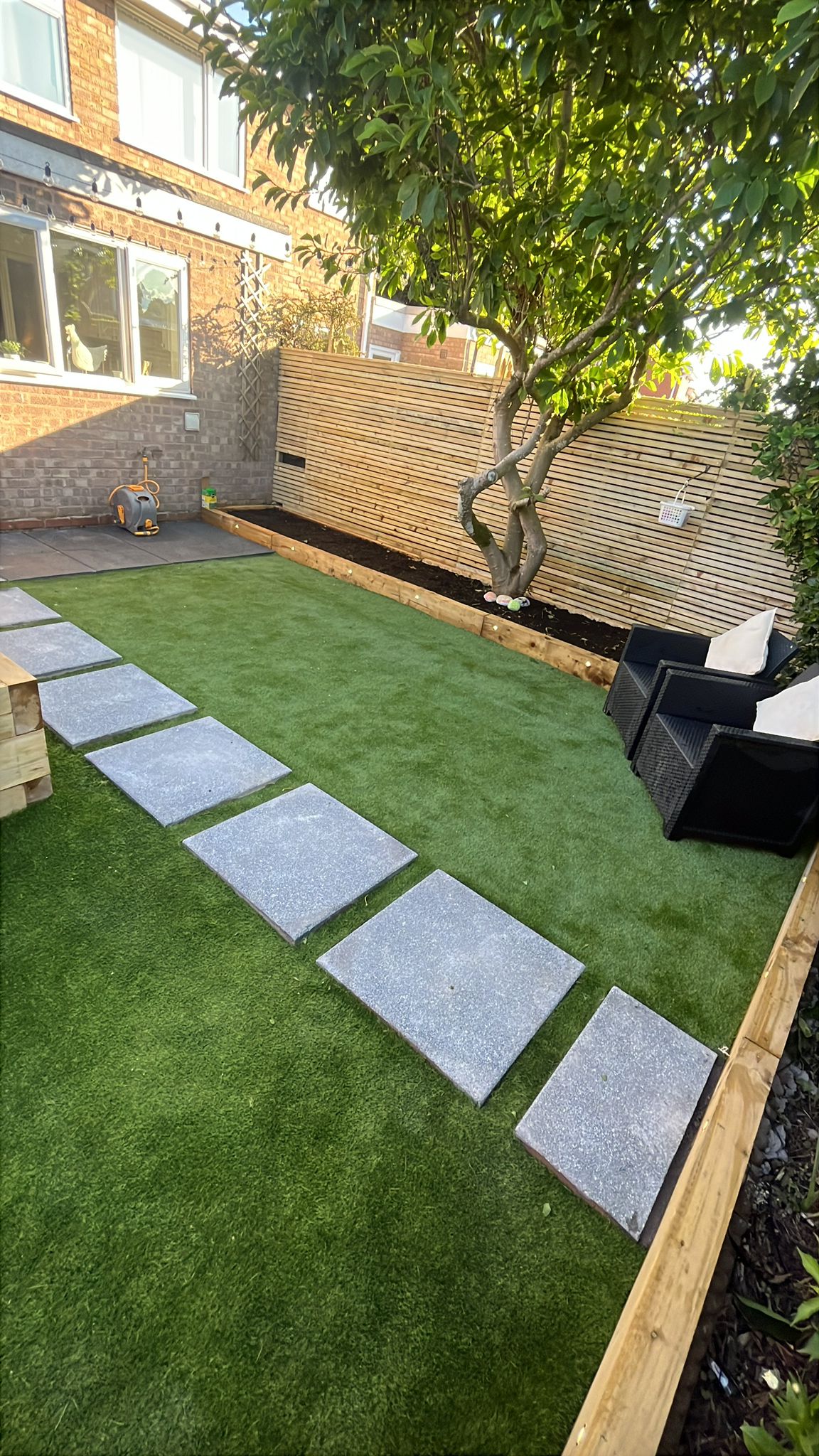Stepping stone path across artificial lawn, seating area